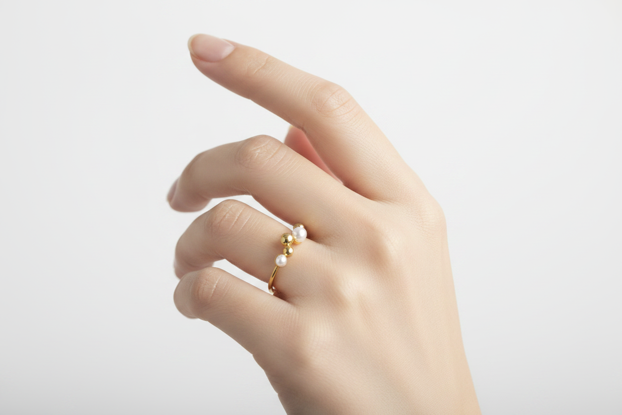 Petite bague dorée perles sur main féminine